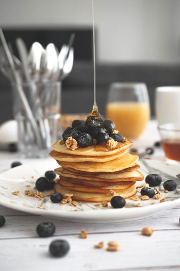 keto syrup pour shot over stack of keto pancakes topped with blueberries.