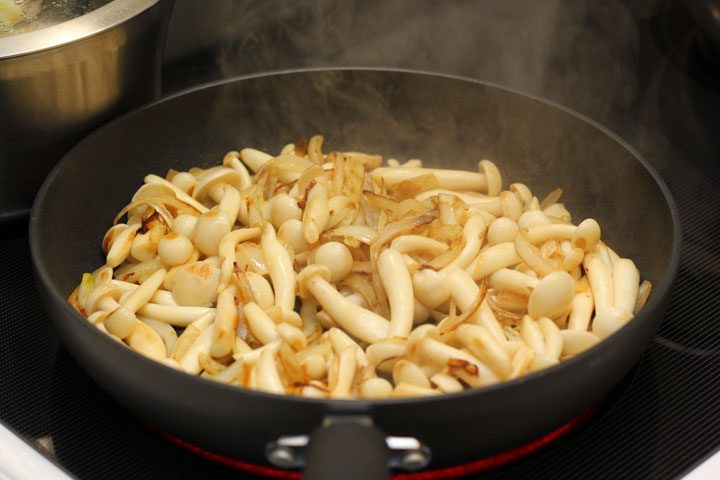vegan tonkotsu ramen preparation sauteing mushrooms on stove.